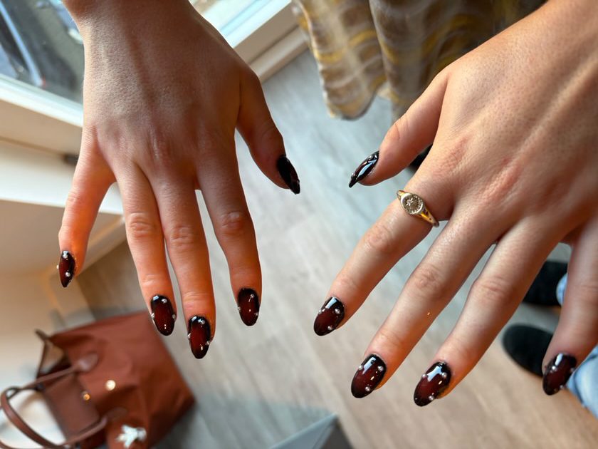 Two hands, right and left, show a fresh set of red stilleto nails.