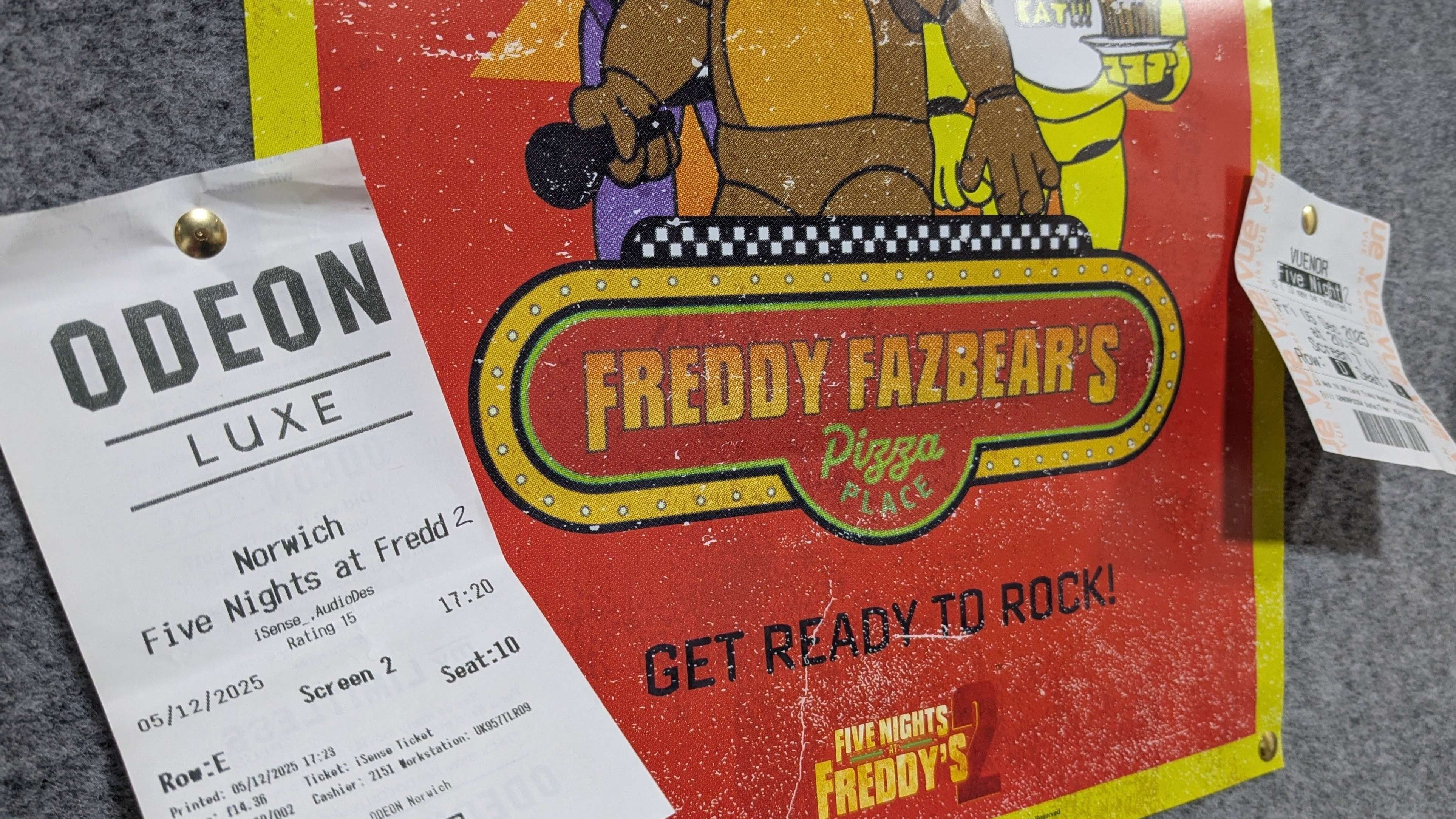 A promotional poster for the Five Nights at Freddy's 2 film is taped to the wall, and two cinema tickets are tacked to it on either side.