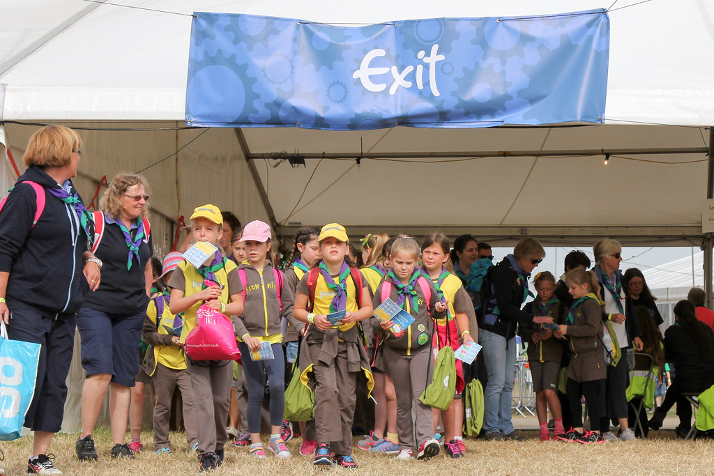 A group of guides, dressed in uniform, look towards the camera. Above them, a sign says exit.