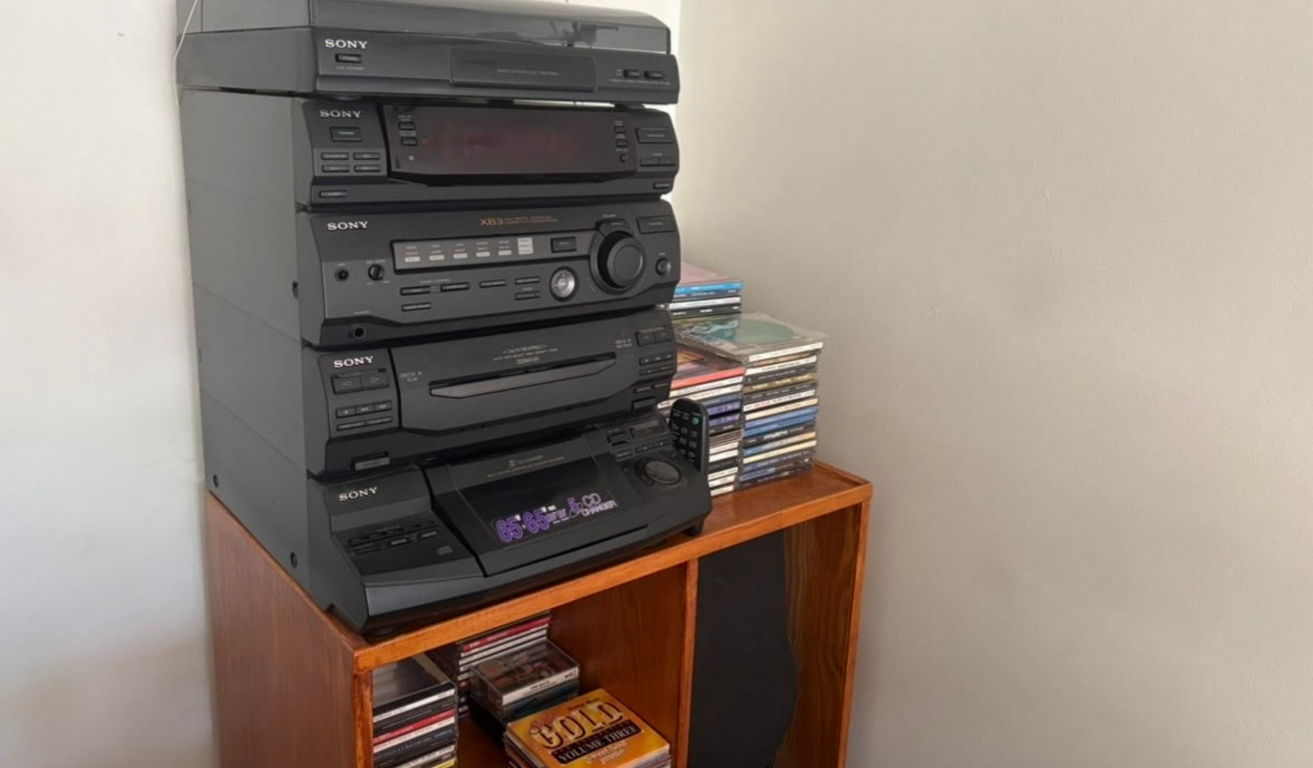 Image of a black music control centre, on top of a wooden unit holding CDs.