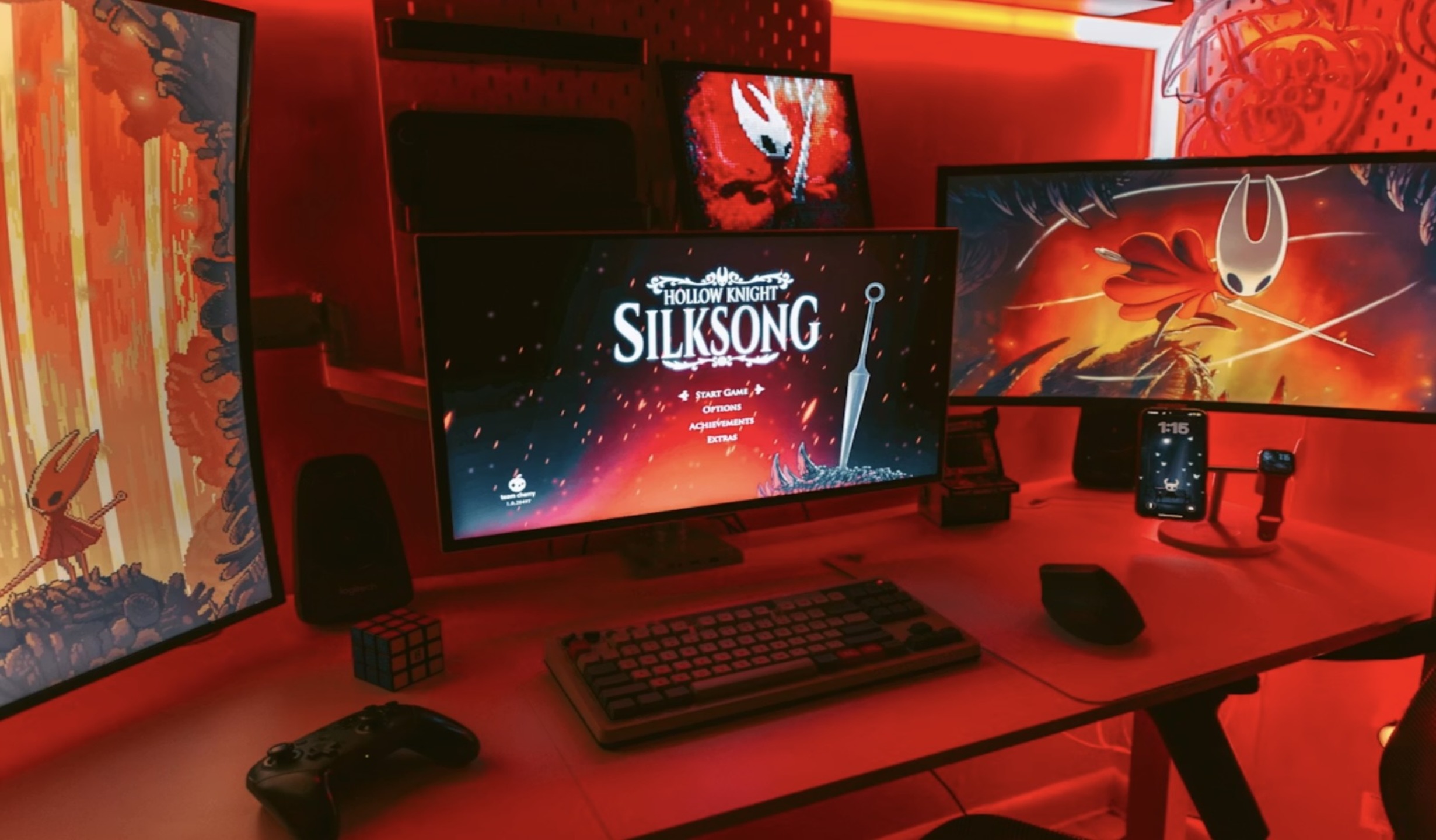 A red lit room, featuring a computer with the Silksong loading screen