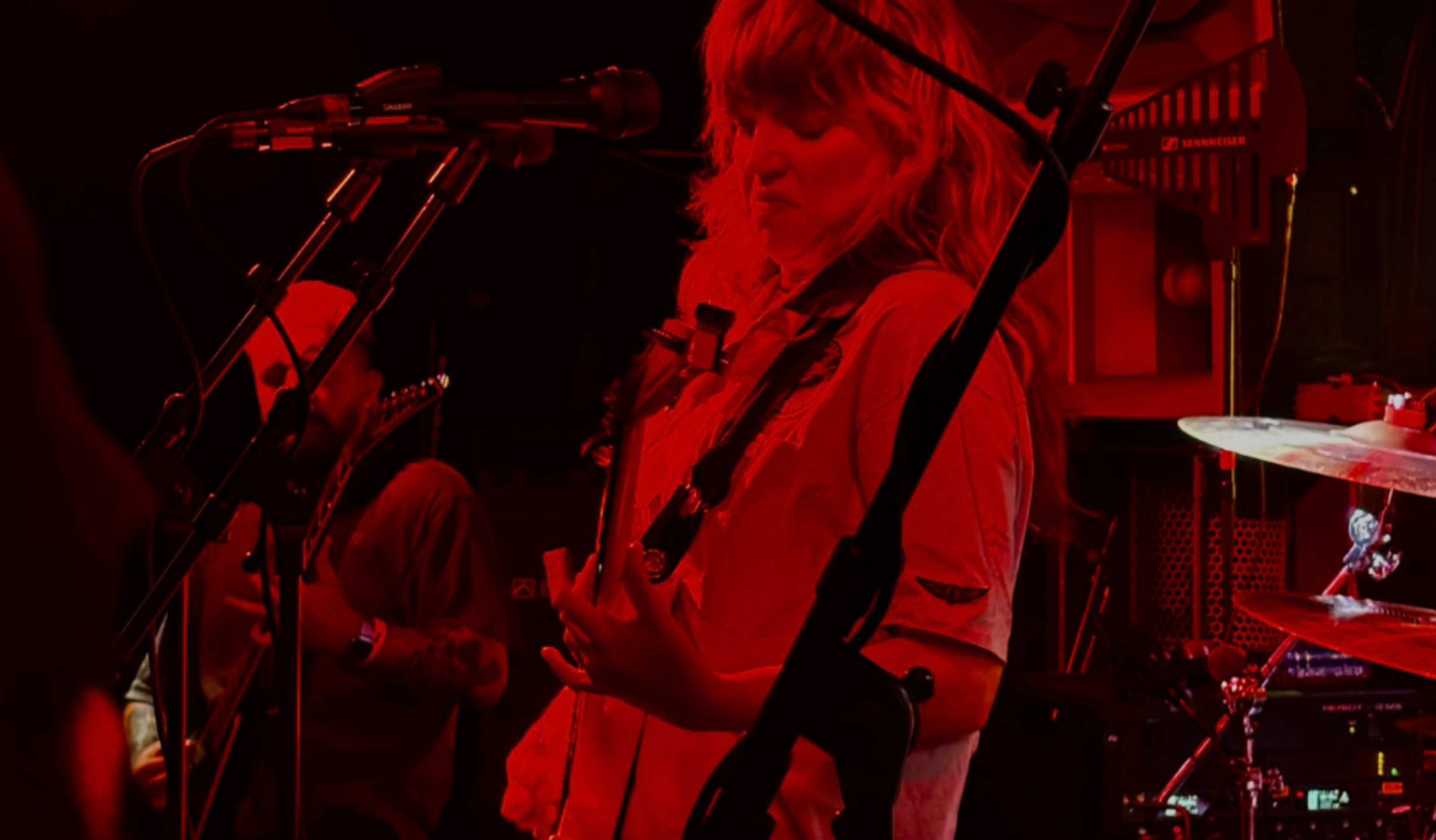 Deb Gough plays guitar in red lit music venue, Voodoo Daddy's