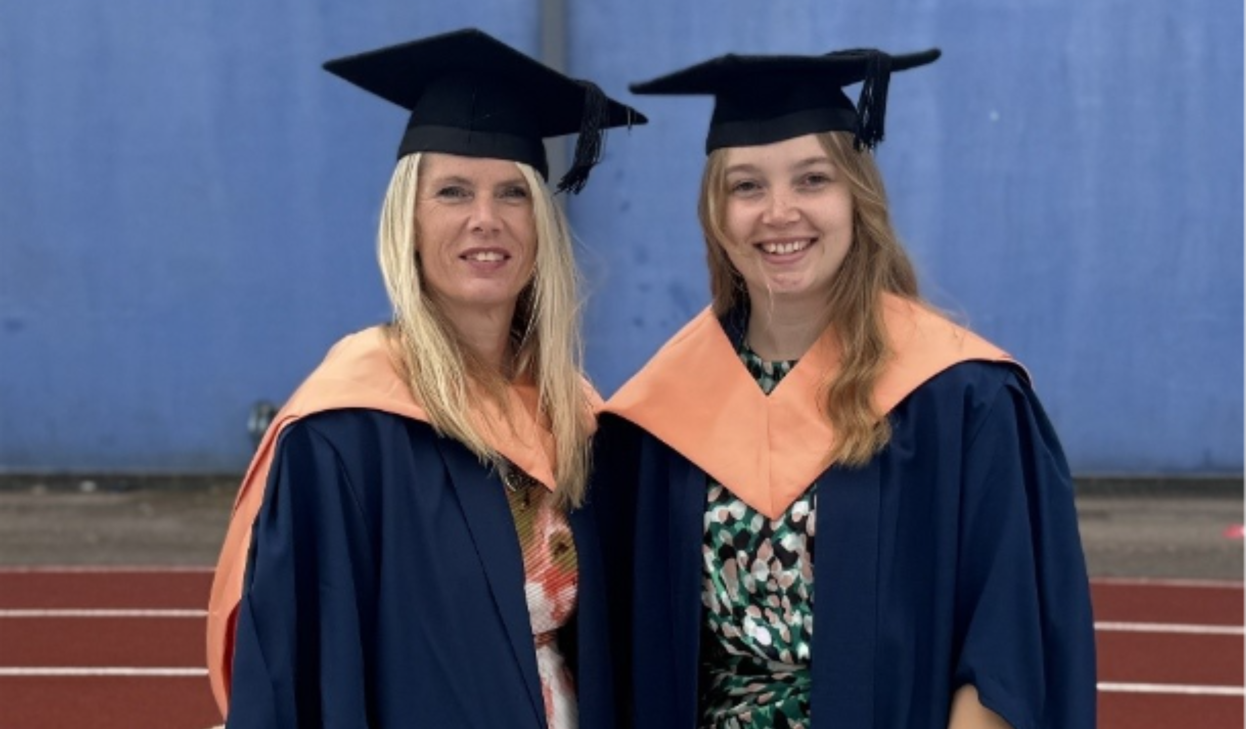 Mother (left) and daughter (right) in graduate robes and caps.