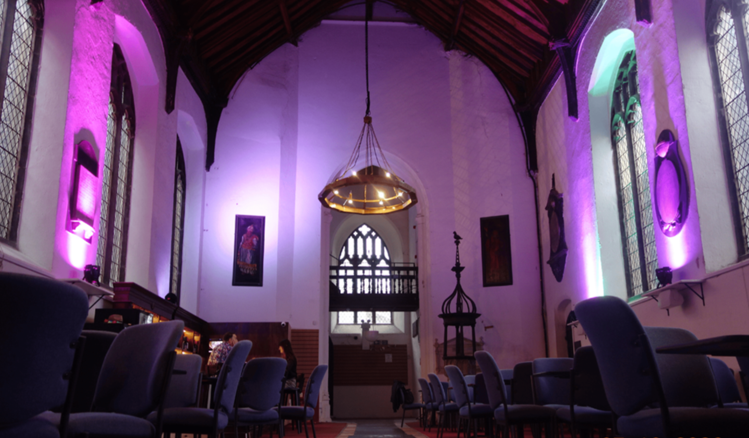a purple lit pub seating area inside a church